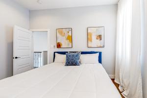 a bedroom with a large white bed with blue accents at Houston's Charmer in Houston