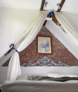 1 cama con cortinas blancas y pared de ladrillo en Cottage sotto il faggio centenario, en Ameno