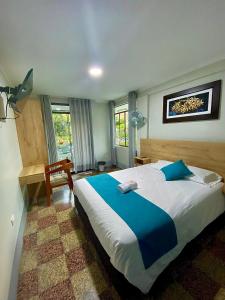 a bedroom with a large bed with a blue blanket at Casa Plaza Bolívar in Quillabamba