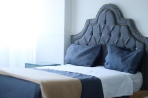 a bed with a blue headboard and pillows at Hotel El Rincón de Jesusita in Durango