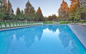 a swimming pool with chairs and trees in the background at The Lodge at Eagle Crest in Redmond