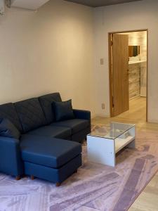 a living room with a blue couch and a glass coffee table at Cloud Sharing Hotel Hakata 1 in Fukuoka