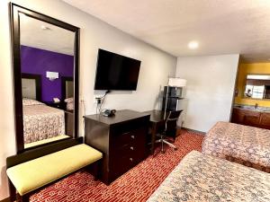 Habitación de hotel con 1 dormitorio con espejo y escritorio. en Magnolia Motel Donaldsonville, en Donaldsonville