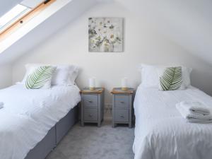 2 bedden in een kamer met witte lakens en kussens bij Pebble Cottage in Middleton-on-Sea