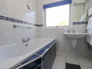 a white bathroom with a tub and a sink at Respryn in Mevagissey +15 photos