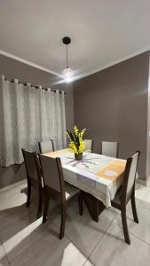 a dining room table with chairs and a vase of flowers on it at casa temporada lua nova centro in Alto Paraíso de Goiás