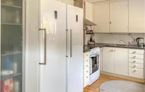 cocina con armarios blancos y nevera en Amazing Apartment In Skrblacka With Kitchen en Skärblacka