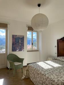Schlafzimmer mit einem Bett, einem Stuhl und Fenstern in der Unterkunft Balconata sul lago in Ameno