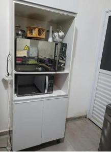 a white cabinet with a microwave in a room at Casa para locação in Atibaia