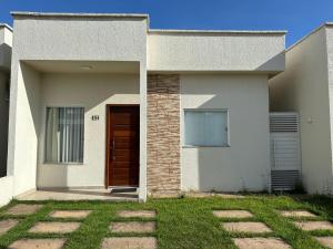 una casa blanca con una puerta marrón y césped en Concierge House Espetacular em Condomínio Fechado, en Marabá