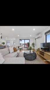 uma sala de estar com um sofá e uma televisão em Spacious House Close to Hobart CBD WiFi and New Sony QLED Smart TV em Moonah