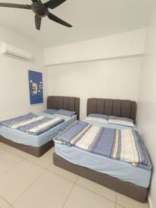 two beds in a room with a ceiling fan at Joyful Sitiawan skygarden swimming pool in Seri Manjung