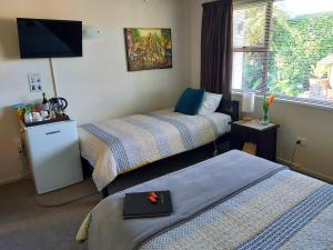 Habitación de hotel con 2 camas y TV de pantalla plana. en Rotorua City Homestay, en Rotorua