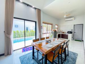 a kitchen and dining room with a wooden table and chairs at 286poolvilla in Suratthani