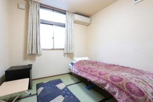 ein kleines Schlafzimmer mit einem Bett und einem Fenster in der Unterkunft プチバスケット in Chiba