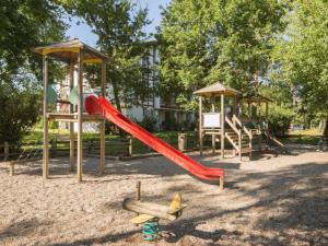 a playground with a red slide and a swing set at Appartement à Biscarrosse avec Piscine, Boulodrome et Terrasse – 7 Personnes, Ménage Inclus - FR-1-319-497 in Biscarrosse