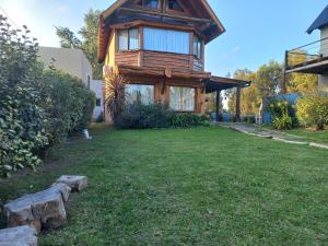 uma casa de madeira com um relvado verde em frente em Espejos de monte em San Miguel del Monte