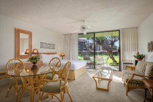 a hotel room with a bed and a table and chairs at Aston at Papakea Resort in Lahaina