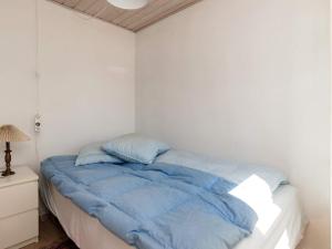 uma cama num quarto branco com um edredão azul em Holiday home Nibe VII em Nibe