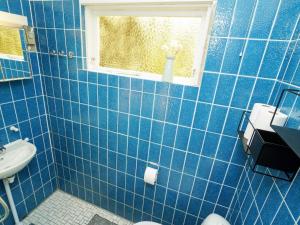 a blue tiled bathroom with a sink and a window at Holiday home Højby III in Højby