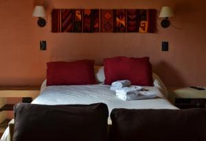 a bed with red pillows and two stuffed animals on it at Cabañas Chacras del Arroyo Vidal in Carpintería