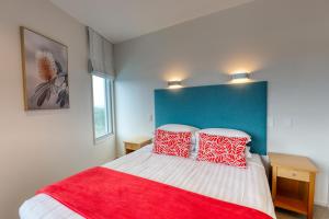 a bedroom with a bed with red and white pillows at Marsden Suites Nautilus Orewa in Orewa