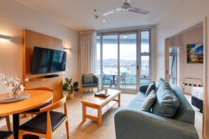 a living room with a blue couch and a table at Marsden Suites Nautilus Orewa in Orewa