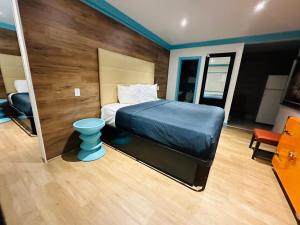 - une chambre avec un lit et un tabouret bleu dans l'établissement Casa Blanca Inn & Suites Whittier, à Whittier
