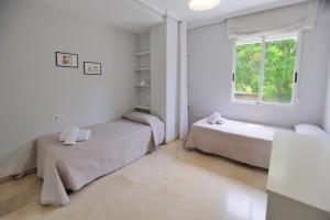 a white room with two beds and a window at Albéniz in Córdoba