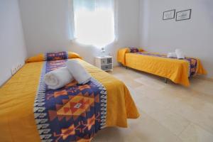 1 dormitorio con 2 camas con sábanas amarillas y ventana en Albéniz, en Córdoba
