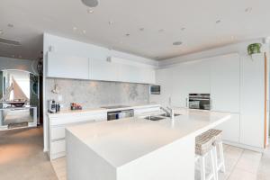 a kitchen with white cabinets and a white counter top at Marsden Suites Nautilus Orewa in Orewa