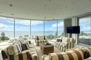 a living room filled with furniture and a flat screen tv at Marsden Suites Nautilus Orewa in Orewa