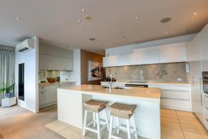 a kitchen with white cabinets and a island with stools at Marsden Suites Nautilus Orewa in Orewa
