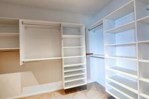 a walk in closet with white shelves at Marsden Suites Nautilus Orewa in Orewa