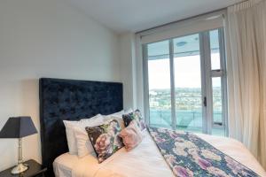 a bedroom with a bed with a large window at Marsden Suites Nautilus Orewa in Orewa
