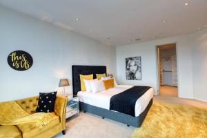 a bedroom with a king sized bed and a couch at Marsden Suites Nautilus Orewa in Orewa