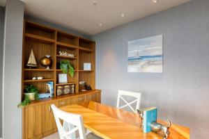 a dining room with a wooden table and a book shelf at Marsden Suites Nautilus Orewa in Orewa