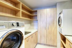 a washer and dryer in a kitchen with wooden cabinets at Marsden Suites Nautilus Orewa in Orewa
