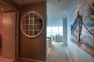a hallway with a round window and a painting on the wall at Marsden Suites Nautilus Orewa in Orewa