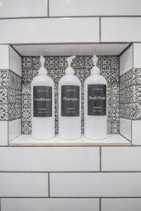 a shelf with three bottles of soap in a bathroom at Casa Cima in Dallas