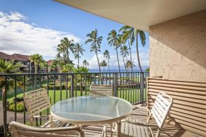 a patio with a glass table and chairs on a balcony at Aston at Papakea Resort in Lahaina