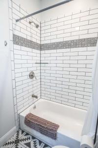 a bathroom with a bath tub with white tiles at Casa Cima in Dallas