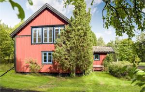 una casa roja con un árbol delante en Amazing Home In Grisslehamn With Sauna en Grisslehamn
