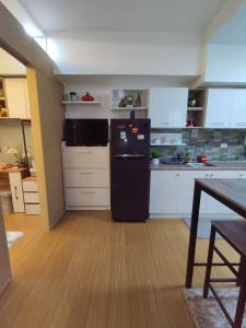 uma cozinha com um frigorífico preto e armários brancos em Maicozy condo em Manila