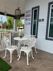 D'LaMar Homestay في Pendang: طاولة بيضاء وكراسي على الفناء