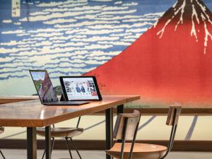two laptops sitting on a wooden table with chairs at Kaneyoshi Ryokan in Osaka
