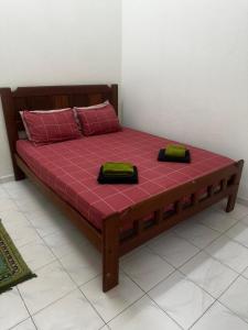 a wooden bed with two pillows on top of it at Sobey Laris Homestay QASEH in Pasir Mas