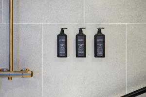 three black shampoo bottles on the wall of a bathroom at Sheraton Hong Kong Hotel & Towers in Hong Kong