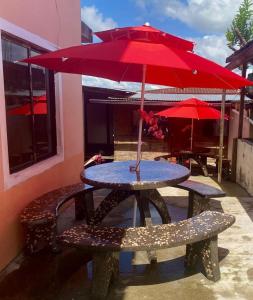 una mesa de picnic con una sombrilla roja en el patio en Casa nómada Puyo, en Puyo