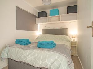 a bedroom with a bed with two blue towels on it at Chalet 54 in Cromer